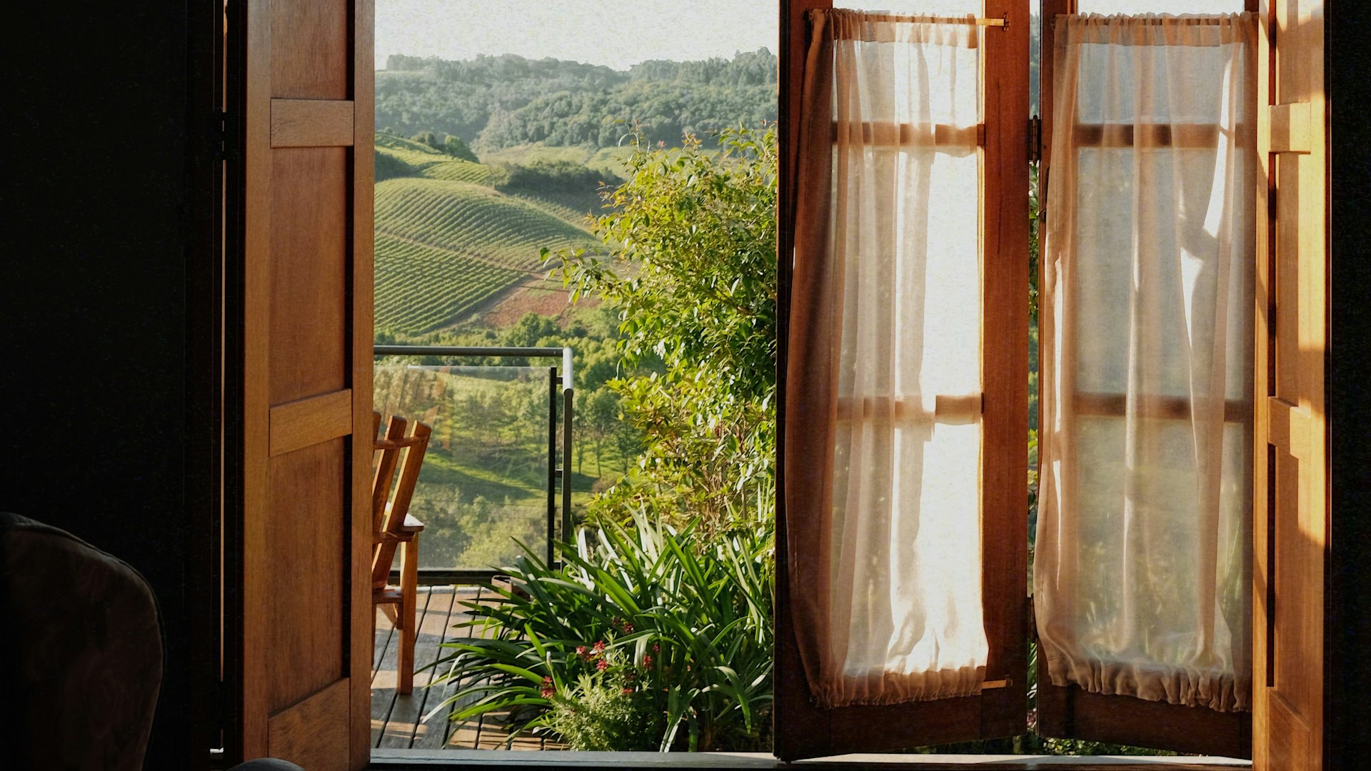 Finestra in legno aperta su una terrazza e sulle colline coltivate a vigneto